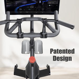 May include: A stationary exercise bike with a digital display showing workout metrics. The bike features a gray handlebar with textured grips, a red adjustment knob, and clear water bottle holders. The text "Patented Design" is visible.