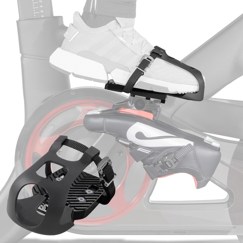 May include: Black exercise bike pedal with adjustable straps. The pedal is designed to secure the user's foot to the bike pedal. The image shows the pedal attached to a shoe and a stationary bike.