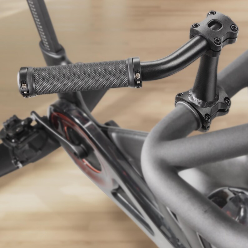 May include: Close-up of a black exercise bike handlebar. The handlebar features a textured grip and is connected to the bike's frame. The bike's frame is a mix of black and silver, with red accents.