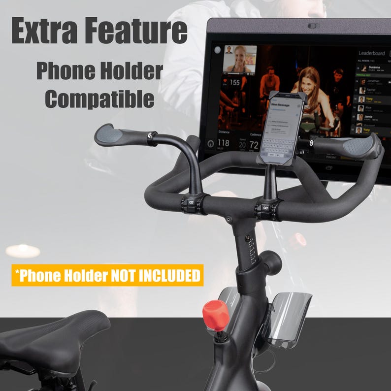 May include: Close-up of a stationary exercise bike with a phone holder. The bike is black with a red knob and a black seat. The text "Extra Feature Phone Holder Compatible" is visible, along with "Phone Holder NOT INCLUDED". A phone is mounted on the handlebars.