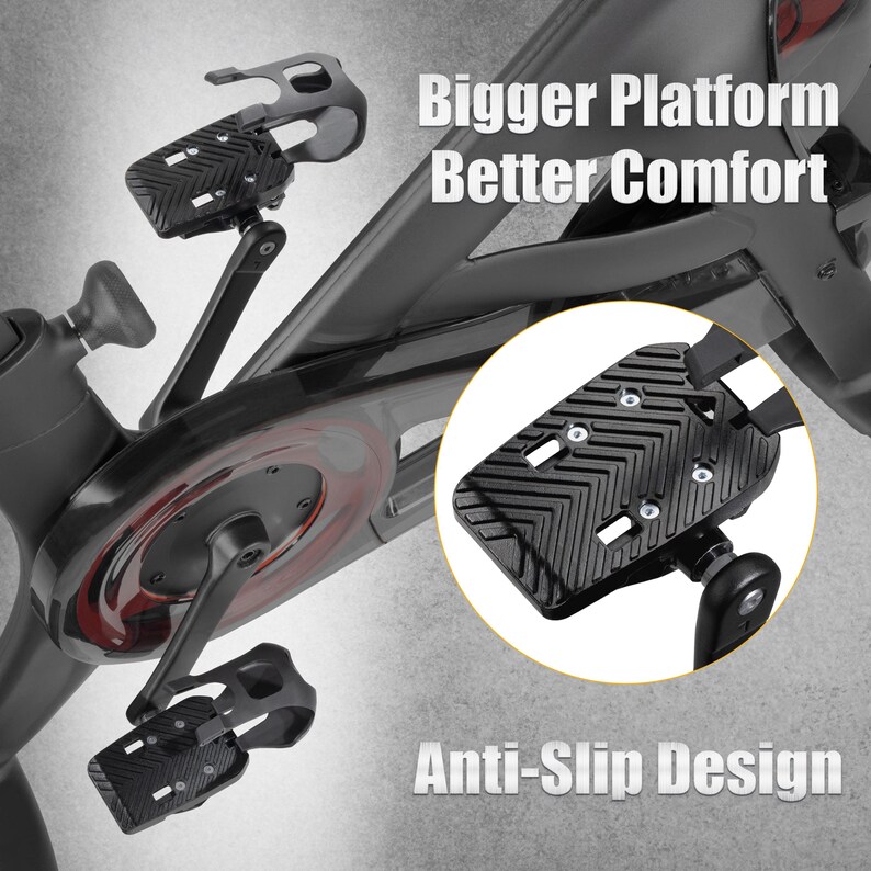 May include: Black exercise bike pedals with a textured, anti-slip surface. The image includes the text "Bigger Platform Better Comfort" and "Anti-Slip Design". The pedals are attached to a stationary bike.