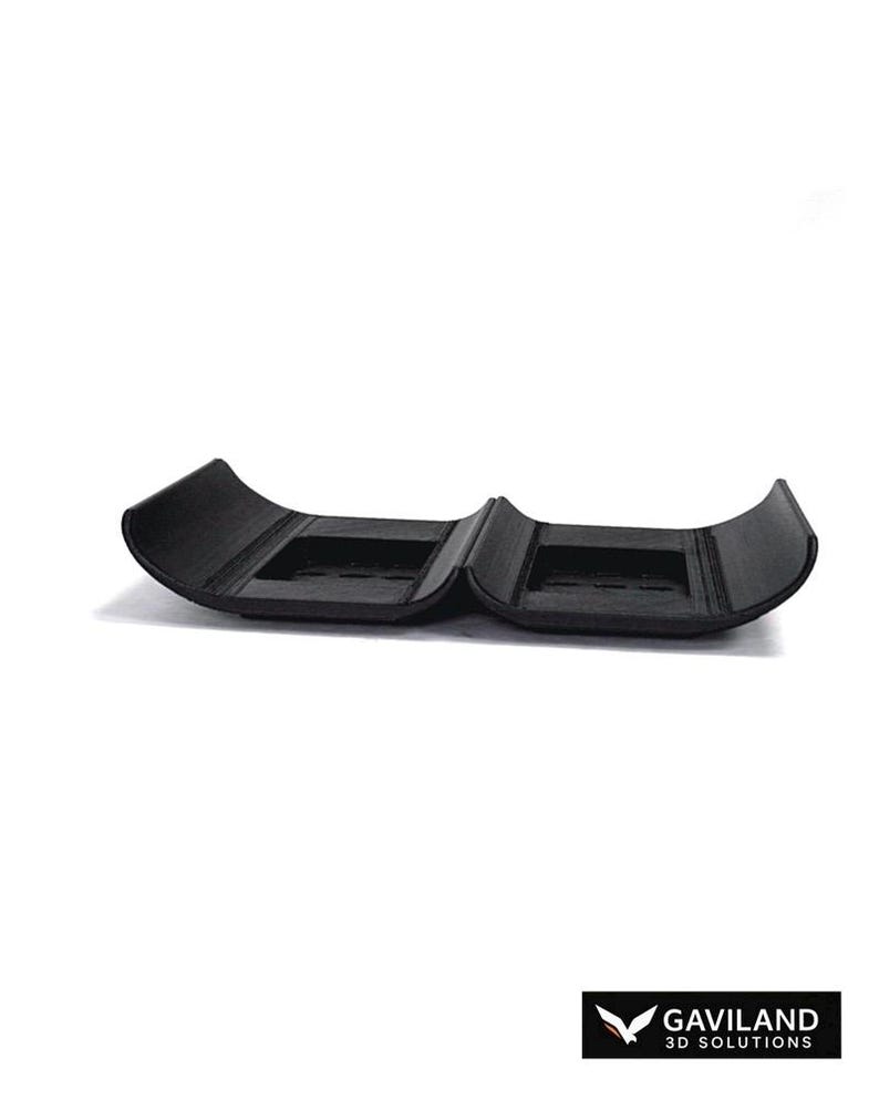 Puede incluir: Un componente de pl&aacute;stico negro impreso en 3D que presenta dos secciones curvas semicil&iacute;ndricas unidas en el centro. Cada secci&oacute;n contiene un &aacute;rea rectangular empotrada con ranuras internas. El logotipo GAVILAND 3D SOLUTIONS es visible en la esquina.