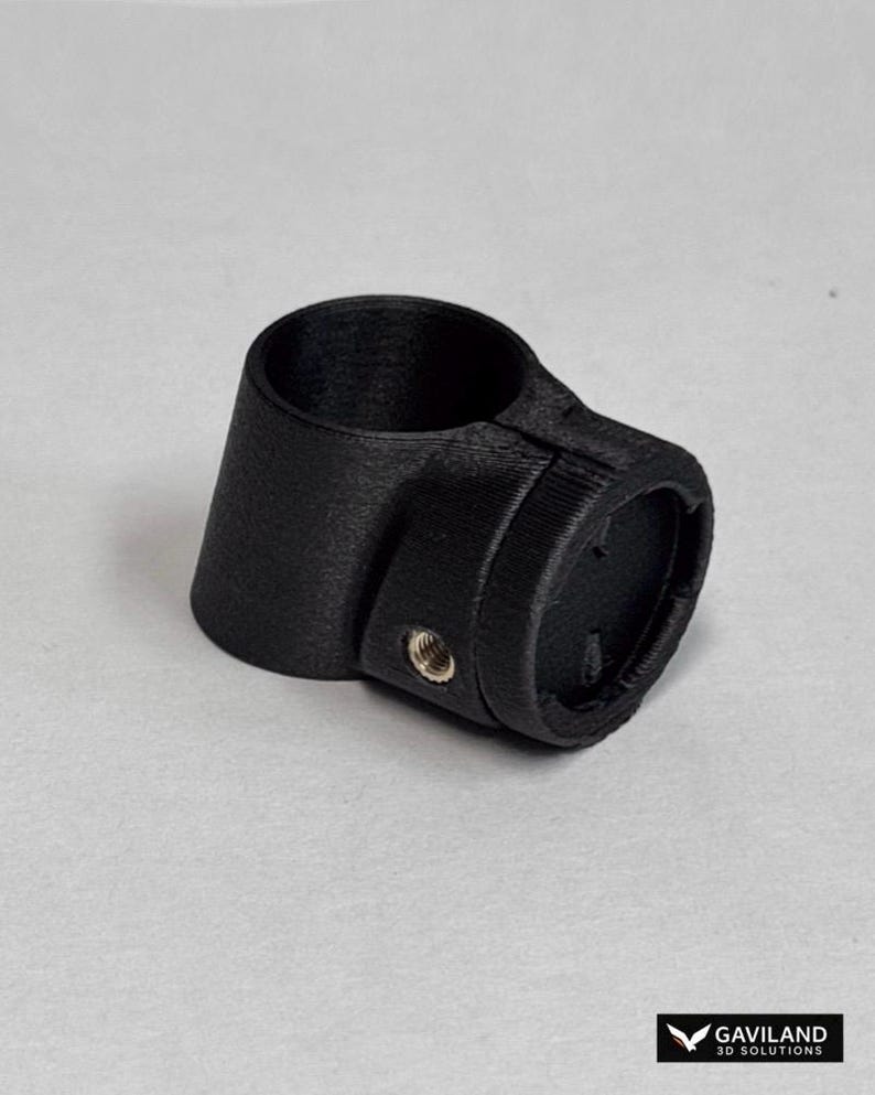 May include: A matte black 3D printed cylindrical mounting bracket featuring a circular opening and a side-mounted metal threaded insert. The component has a textured surface finish and includes the text GAVILAND 3D SOLUTIONS in the corner.