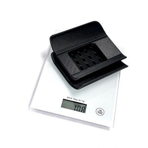 Puede incluir: Un objeto de pl&aacute;stico negro de forma rectangular impreso en 3D, con una rejilla de peque&ntilde;os orificios en su superficie superior, colocado sobre una b&aacute;scula de cocina digital blanca. La b&aacute;scula muestra el texto MAX 5kg d=1g y 108 gramos.