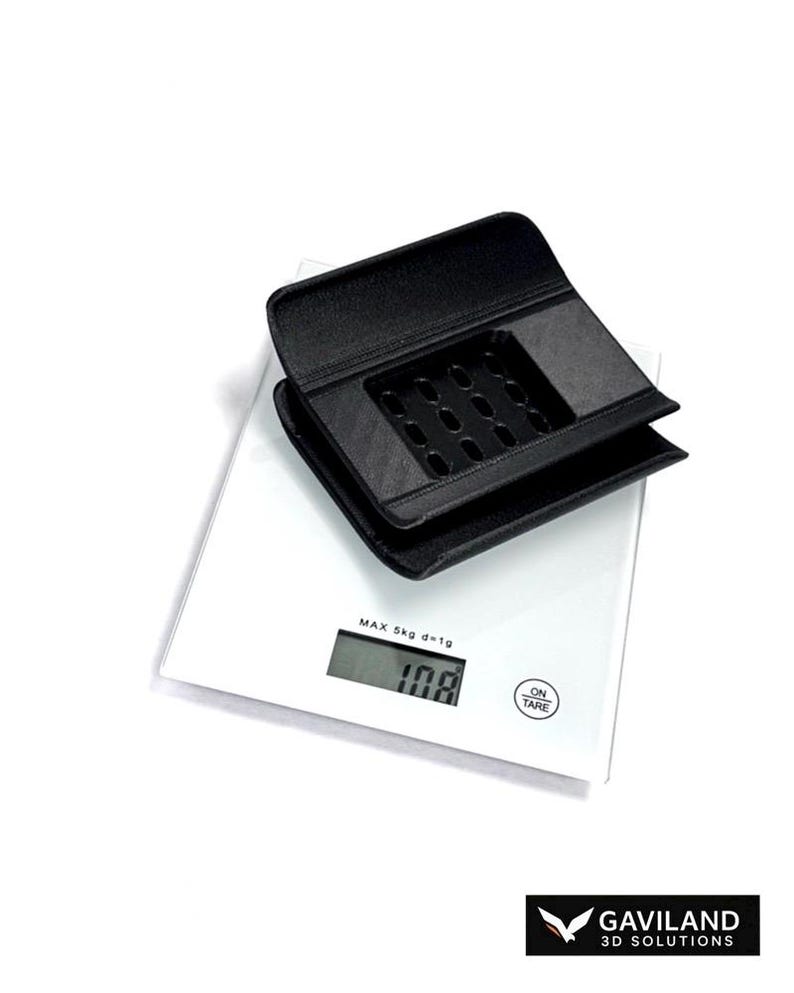Puede incluir: Un objeto de pl&aacute;stico negro de forma rectangular impreso en 3D, con una rejilla de peque&ntilde;os orificios en su superficie superior, colocado sobre una b&aacute;scula de cocina digital blanca. La b&aacute;scula muestra el texto MAX 5kg d=1g y 108 gramos.