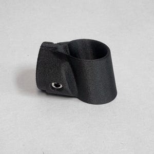 May include: A matte black, 3D-printed cylindrical pipe connector featuring a textured surface and a single integrated metal bolt head on the side. The component has a tapered design with a hollow center, designed for structural assembly and joining.