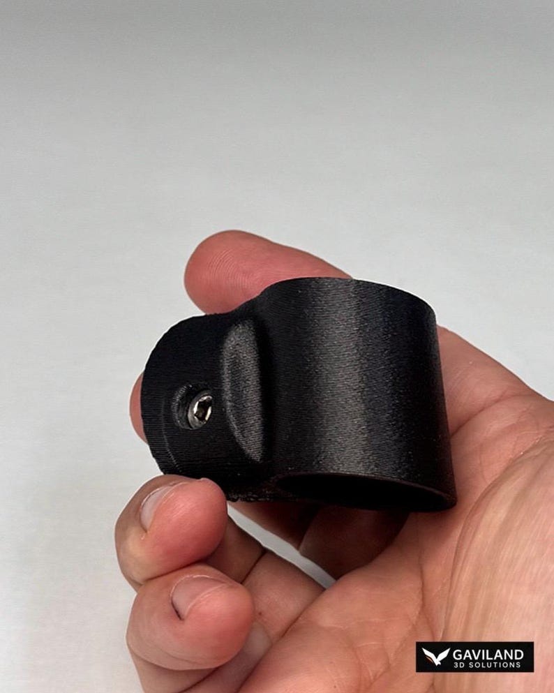 May include: A black, cylindrical, 3D-printed plastic clamp featuring a protruding side mount with a single integrated metal screw. The component has a textured surface finish and a hollow center, designed for securing cylindrical objects.