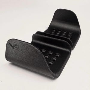 May include: A black, textured, U-shaped holder with two curved sections featuring rows of small circular indentations. The object has a matte finish and a small embossed logo on the front left side. The text GAVILAND 3D SOLUTIONS is visible.