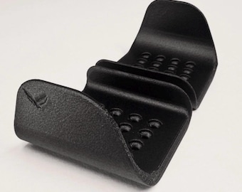 May include: A black, textured, U-shaped holder with two curved sections featuring rows of small circular indentations. The object has a matte finish and a small embossed logo on the front left side. The text GAVILAND 3D SOLUTIONS is visible.