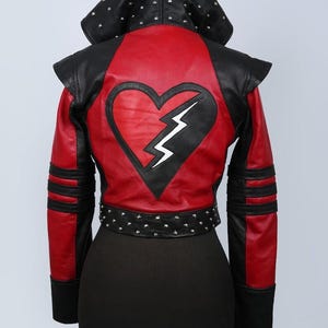 May include: A black and red hooded jacket featuring a large black heart appliqué with a white lightning bolt cutout on the back. The jacket includes silver metal studs along the hood and waist belt, with black textured shoulder panels and sleeves.