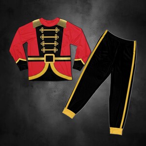 May include: A long-sleeve shirt and pants set featuring a red and black soldier uniform design. The shirt has gold braided trim, epaulets, and a belt graphic. The black pants include a gold side stripe and gold cuffs at the bottom of the legs.