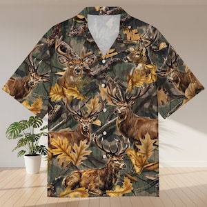 May include: Short-sleeved shirt with a deer and camouflage design. The shirt displays a repeating pattern of deer, autumn leaves, and a camouflage background in brown, green, and yellow hues.