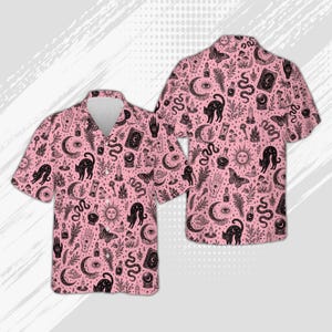 Puede incluir: Una camisa de manga corta con botones en color rosa claro con un estampado negro estilo tinta en toda la prenda. El patrón incluye ilustraciones de gatos, serpientes, polillas, lunas crecientes, soles, bolas de cristal y manos.