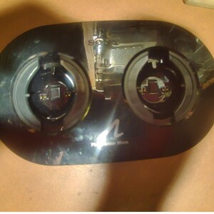 May include: Black PlayStation Move charging station with two circular charging ports. The station has a glossy finish and the PlayStation Move logo is visible. The device is designed to charge PlayStation Move controllers.