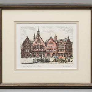 Peut inclure: Une gravure encadrée de la place de la ville de Francfort-sur-le-Main représentant des bâtiments historiques à pignons dans des tons rose et brun, une fontaine centrale et des étals de marché. L'œuvre est signée et sous un cadre en bois sombre.