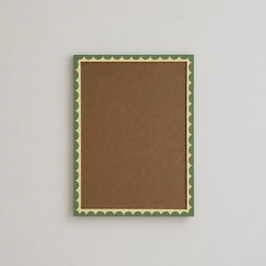 Puede incluir: Un marco de fotos rectangular con un borde verde oscuro y un borde interior festoneado en color crema claro. El centro del marco está relleno con un material de fondo marrón sólido, creando una exhibición simple y limpia para fotos.