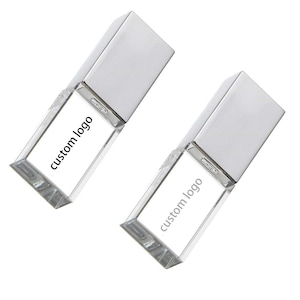 Puede incluir: Dos unidades flash USB rectangulares transparentes con tapas plateadas. Las unidades tienen el texto "custom logo" impreso. El fondo es blanco.