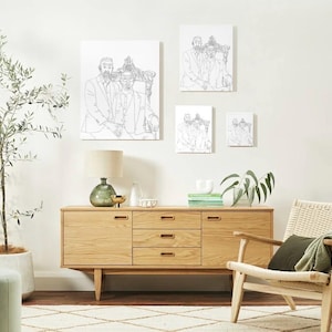 Puede incluir: Un salón con un aparador de madera, una silla de mimbre con un cojín y una manta verdes, y una lámpara de pie. Encima del aparador, cuatro retratos enmarcados. Un olivo en maceta y un puf verde completan la decoración.