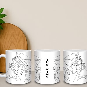 Könnte beinhalten: Weiße Keramik-Tasse mit einer schwarzen Strichzeichnung einer Person mit Hut und Handschuhen. Der Text "THE KING" ist vertikal auf der Tasse aufgedruckt. Die Tasse hat einen weißen Henkel.