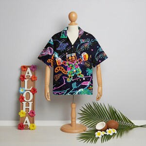 Puede incluir: Camisa hawaiana negra con un gráfico de gato de neón sosteniendo jarras de cerveza, rodeado de criaturas marinas. El diseño de la camisa incluye un tiburón, pizza y una hamburguesa. La camisa tiene un cuello clásico.