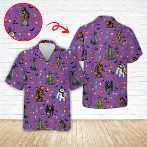 May include: A short-sleeve button-down shirt in purple featuring an all-over Halloween print. The pattern includes illustrations of cryptids like Bigfoot, a yeti, and a swamp creature, alongside pumpkins, witch hats, bats, and UFOs.
