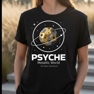 May include: Black t-shirt featuring a graphic of a geometric planet with gold and gray panels, encircled by a white ring and stars. The word "PSYCHE" is above "Metallic World" and "The Next Gold Rush" in white text.