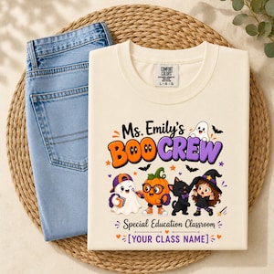 May include: A cream-colored t-shirt featuring a graphic with the text Ms. Emily's BOO CREW and Special Education Classroom. The design includes a ghost, a pumpkin with glasses, a black cat, and a character in a witch hat, plus the text YOUR CLASS NAME.