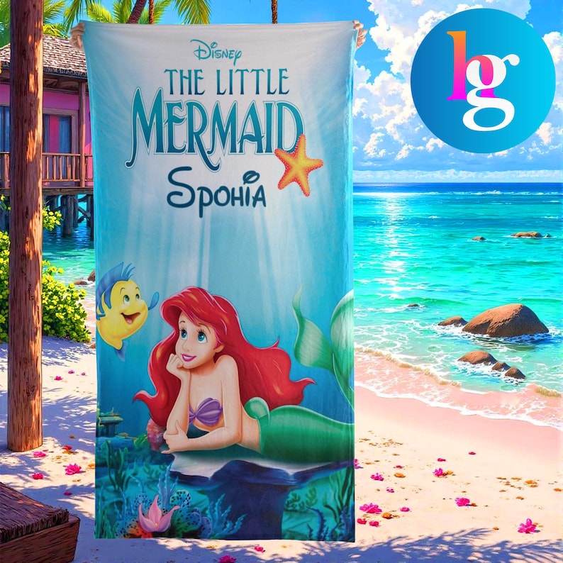 a Disney-themed towel with the character Ariel from The Little Mermaid, set against a beach backdrop with palm trees and a clear blue sky.