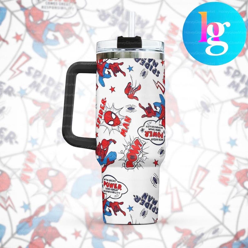 A white tumbler with a handle and a straw, decorated with a Spider-Man theme. The tumbler has a repeating pattern of Spider-Man characters and phrases, such as "SPIDER-MAN", "POW", and "POWER".