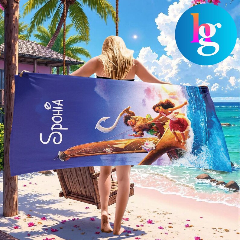 A woman is standing on a beach holding a large towel with a colorful design featuring a surfer and palm trees.