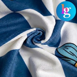 The image is a close-up of a fabric with a blue and white checkered pattern, featuring a small graphic design on the right side.