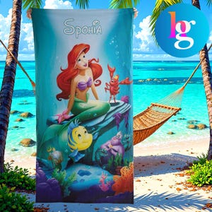 A large beach towel featuring the character Sphero from the Disney animated film "The Little Mermaid". The towel is hanging on a beach with palm trees and a hammock in the background.