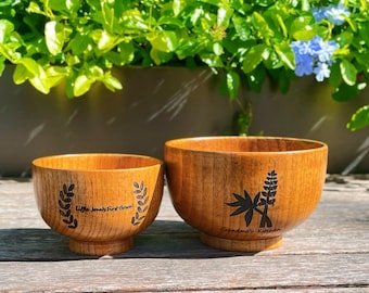 May include: Two wooden bowls with a warm, natural finish. The smaller bowl has the text "Little Jonah's First Bowl" and a leaf design. The larger bowl features the text "Grandma's Kitchen" and a botanical illustration.