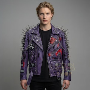 Può includere: Giacca di pelle viola con borchie argentate sulle spalle e sul colletto. La giacca presenta borchie, catene e toppe argentate con testo e grafica. Ha una cintura e una chiusura con cerniera. Il testo "FUCK OFF" è visibile.