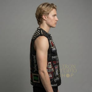 Close up side view of studded leather biker vest with metal patches and details.