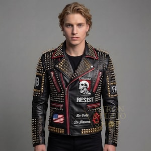 Può includere: Giacca in pelle nera con dettagli dorati e rossi, caratterizzata da numerose borchie dorate sulle spalle e sulle maniche. La giacca presenta una toppa con un teschio con la scritta "RESIST" e una toppa con la bandiera americana. È visibile anche il testo "No Gods No Masters".