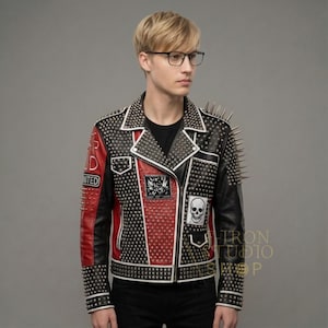 May include: Black and red leather jacket with silver studs and spikes. The jacket features a white trim, patches, and a skull design. The sleeves and shoulders are adorned with long silver spikes. The jacket has a classic biker style.