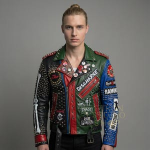 May include: A multi-colored leather jacket with a punk rock aesthetic. The jacket features a mix of black, red, green, and blue panels, adorned with metal studs, patches, and pins. The design includes the words "DISCHARGE", "RAMONES", and "SEX PISTOLS".