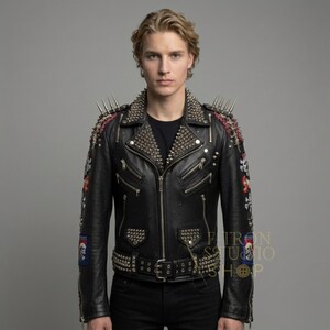 May include: Black leather jacket with silver metal studs and spikes on the shoulders and collar. The jacket has multiple zippers, a belt with studs, and patches on the sleeves. The jacket is worn over a black shirt.