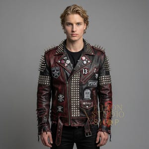 May include: A black and burgundy leather jacket with silver studs and spikes. The jacket features patches with the words "Police", "13", and "Psycho". The sleeves have a distressed look, and the jacket has a zipper closure and belt.