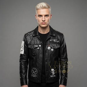May include: Black leather jacket with silver spikes on the shoulders. The jacket features patches with spiderwebs, band logos, and pins. The jacket is buttoned up and has a classic collar.
