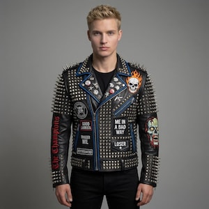 Può includere: Giacca in pelle nera con borchie argentate, finiture blu e toppe con teschio, fiamme e testo. La giacca ha una chiusura con cerniera.