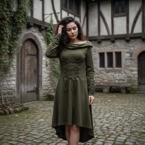 May include: An olive green dress with a corset-style bodice and long sleeves. The dress has a high-low hemline and a cowl neckline. The sleeves are gathered at the wrists. The dress is made of a soft, textured fabric.