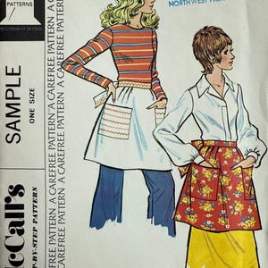 May include: Vintage McCall's sewing pattern for Misses' and Junior short aprons. The illustration shows two aprons: one white with pockets and the other red with a floral pattern. The pattern includes the text "A Carefree Pattern".