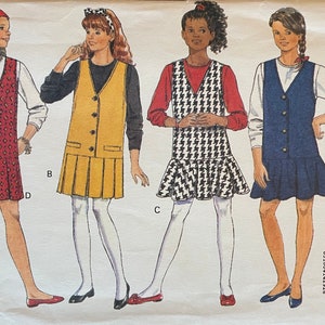 May include: A sewing pattern for a sleeveless dress with a V-neckline and a ruffle hem. The pattern is called "Sarah" and is from Butterick pattern number 6369. The pattern includes four different dress styles: a red and white patterned dress, a yellow dress, a black and white houndstooth dress, and a blue dress.