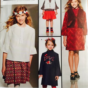 May include: A sewing pattern for children's clothing, featuring three different designs. The pattern is for sizes 3-6 and is inspired by Project Runway. The pattern includes a white blouse with a ruffled collar, a red and white patterned skirt, a white vest with a red skirt, and a red dress with a brown vest.