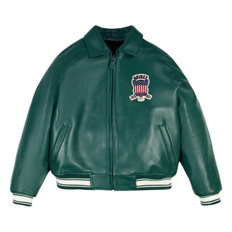 May include: A dark green leather jacket with a collared neckline and a zipper closure. The jacket features a white and black striped trim on the cuffs and hem. An embroidered patch with the word "AVIREX" and a patriotic design is on the chest.