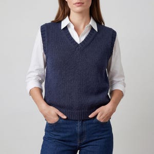 May include: A white ceramic mug with a black handle and the text "But First, Coffee" in a bold, black font. The mug is set against a blurred background, suggesting a cosy setting.