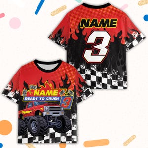 May include: Red and black graphic t-shirt featuring a monster truck design. The shirt has the word "NAME" and the number "3" on the front and back. The front of the shirt also has the text "READY TO CRUSH".