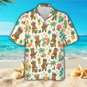 Op de afbeelding: Crème Hawaii-shirt met een herhaald patroon van tiki-figuren die muziekinstrumenten bespelen, surfplanken, palmbomen, ananassen en bloemen. Het shirt heeft korte mouwen en een knoopsluiting. De achtergrond toont een strandscène.